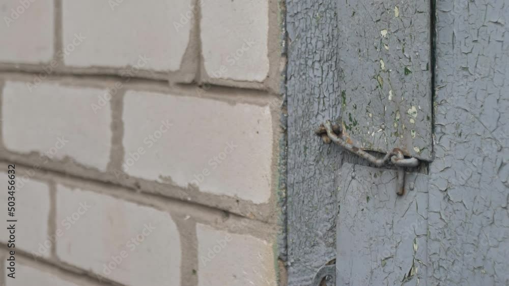 an old woman uses a metal door hook to close an old door.close-up an old woman uses a metal door hook to close an old door.close-up