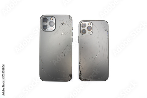 Two space grey modern smartphones has broken back glass on white background.