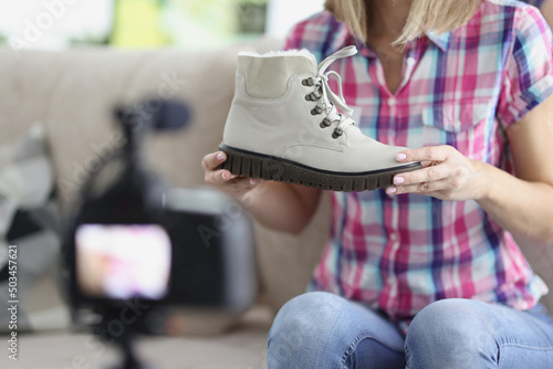 Woman present trendy white boot showing on camera, try to sell online