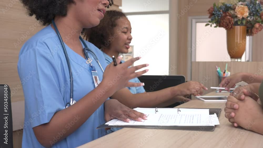 Group of Young female nurse work at clinic reception desk. She is helping to patient to make contactless payment for medical services. Physician at work in clinic. Medicine and health care concept. Group of Young female nurse work at clinic reception desk. She is helping to patient to make contactless payment for medical services. Physician at work in clinic. Medicine and health care concept.