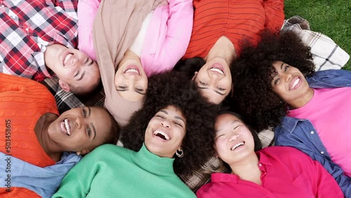 group of multiracial women lying on the grass, happy women smiling happily on a day in the park