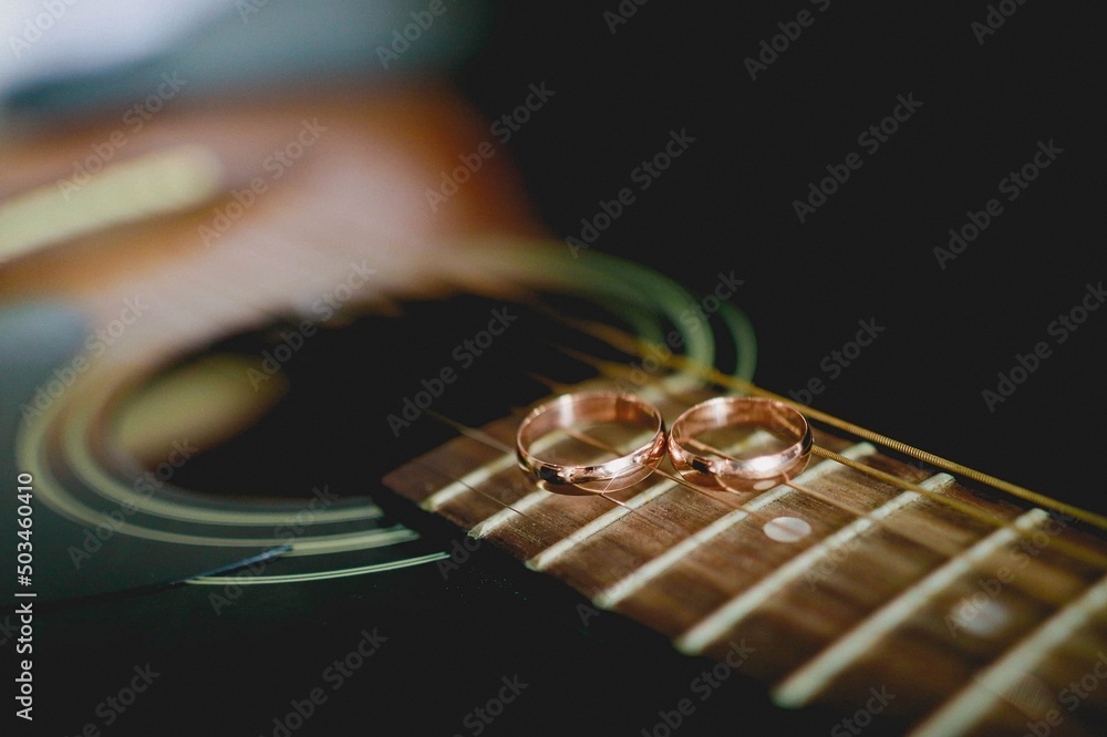 Wedding rings lie on the strings of a guitar Wedding rings lie on the strings of a guitar