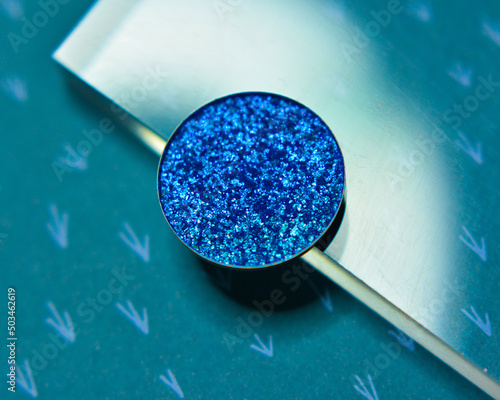 Single glittery deep blue eye shadow on darl blue background with acrylic