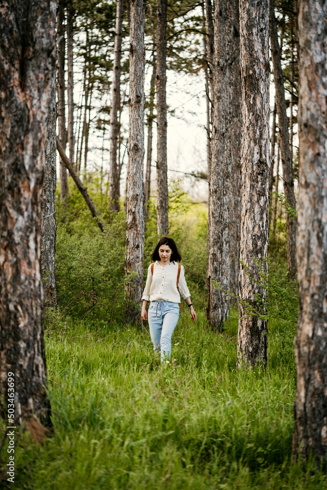 Young woman with backpack walking alone in a forrest