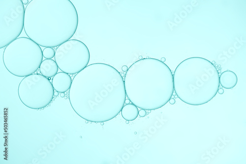 Oil bubbles in water on pale blue background.