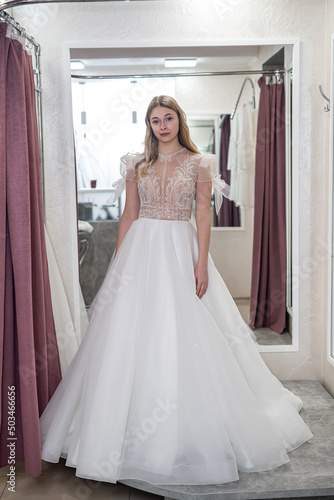 young prety woman is trying white wedding dresses