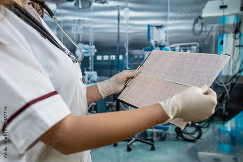 Young female doctor looks at the cardiogram of the heart to patient at operating room on hospital