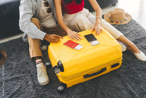 Young adult southeast asian couple hand place on luggage with passport for getting ready for holidays travel photo