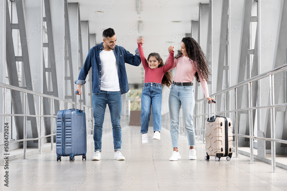 Fototapeta premium Happy Arab Family Of three Having Fun Together While Walking In Airport