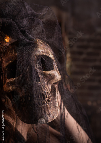 Halloween. Human skull in girl's hands. Under a black veil