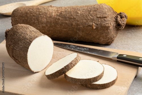  Whole and sliced raw African yam on a cutting board close up photo