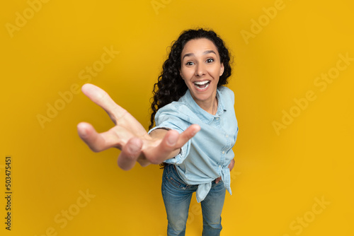 Excited young woman outstretching hand, trying to grab something photo