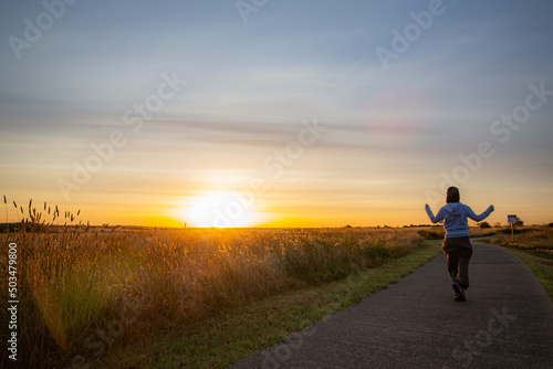 Sunrise view in Australia with a girl dancing walking on the park trail, orange, egg yolk colour with cloudy blue sky