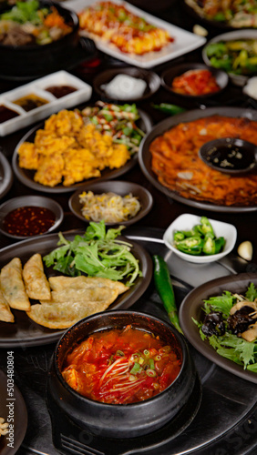 Korean Grilled BBQ combo sets on the traditional grill table, kimchi soup, fried dumplings, pancake, fried chicken, pickle dishes