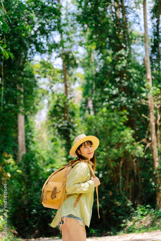 Woman traveling in forest nature with backpack and straw hat.