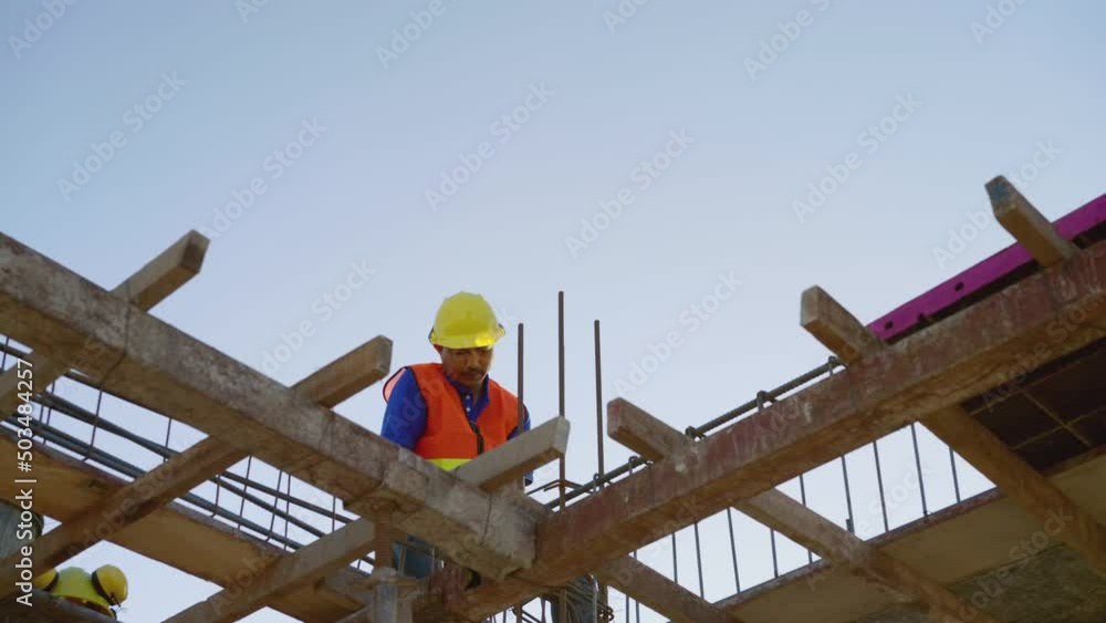 Construction worker are tying iron on high ground. Asian man wearing safety uniform and hard hats working in a building site Construction worker are tying iron on high ground. Asian man wearing safety uniform and hard hats working in a building site