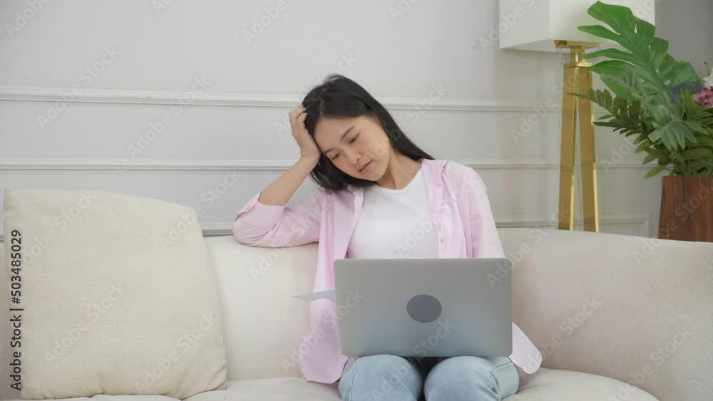 Young asian woman stress sitting on sofa reading notification document about loan and expense finance while worried and unhappy and shocked at home, financial and invoice letter, business concept. Young asian woman stress sitting on sofa reading notification document about loan and expense finance while worried and unhappy and shocked at home, financial and invoice letter, business concept.