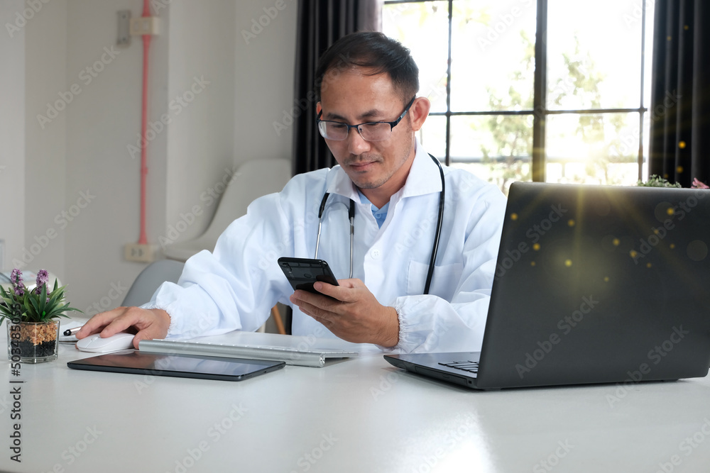 Close-up of a doctor sitting and working with a laptop in his clinic. A young doctor at work. Excellent medical service and medical concept Close-up of a doctor sitting and working with a laptop in his clinic. A young doctor at work. Excellent medical service and medical concept