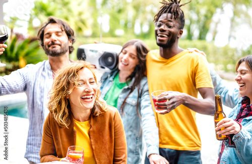 Multiracial friends group having fun out side cheering with boombox and fancy drinks - Gen z people enjoying spring break party festival together - Youth life style concept on bright warm filter