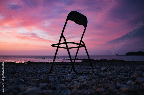 Silhouette of a beach chair against a beautiful sunset sky photo