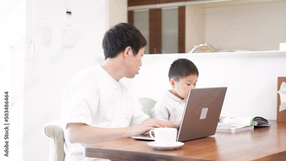 子供の面倒を見ながら家で仕事をする男性 子供の面倒を見ながら家で仕事をする男性