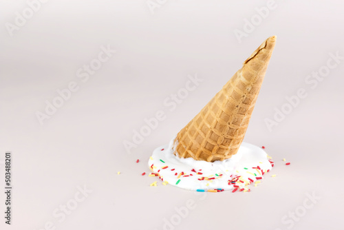 Melting ice cream with waffle cone on pastel color backgrounds. Summer creative food concept.