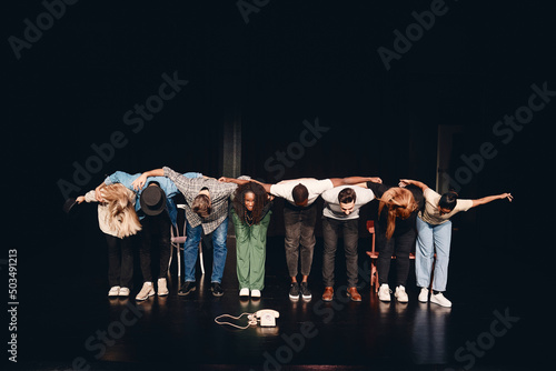 Full length of multiracial male and female artists bowing together on stage