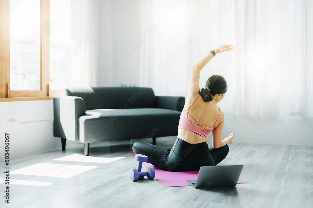 Fototapeta premium stress relief, muscle relaxation, breathing exercises, exercise, meditation, portrait of Young Asian woman relaxing her body from office work by practicing yoga by watching online tutorials.