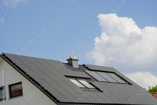 Fotovoltaik Module auf einem Wohnhaus Dach. Im Hintergrund türmen sich die Wolken auf