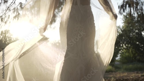 The bride's wedding dress is fluttering and the sun is penetrating it. photo