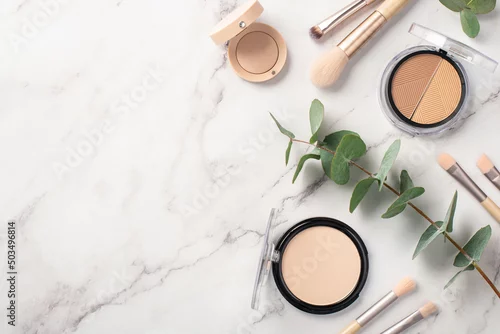 Obraz Make-up concept. Top view photo of makeup brushes contouring palette eyeshadow compact powder and eucalyptus on white marble background with empty space