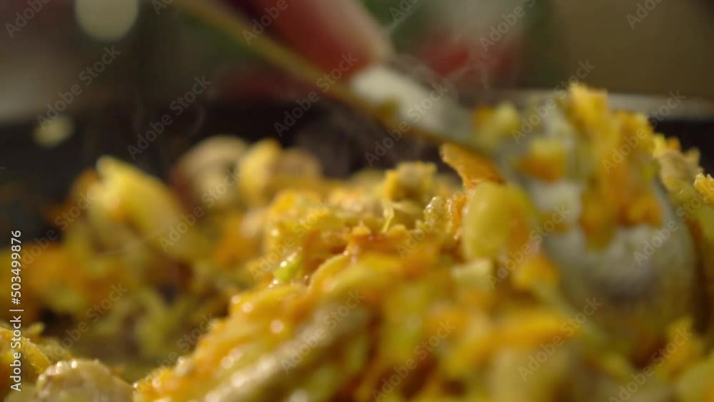 Frying pan with meat and vegetables close-up. Hand of women with spoon mixes contents. Preparation of gravy, goulash or sauce. Vegetarian food. Chinese. Housewife prepares homemade meals. Frying pan with meat and vegetables close-up. Hand of women with spoon mixes contents. Preparation of gravy, goulash or sauce. Vegetarian food. Chinese. Housewife prepares homemade meals.