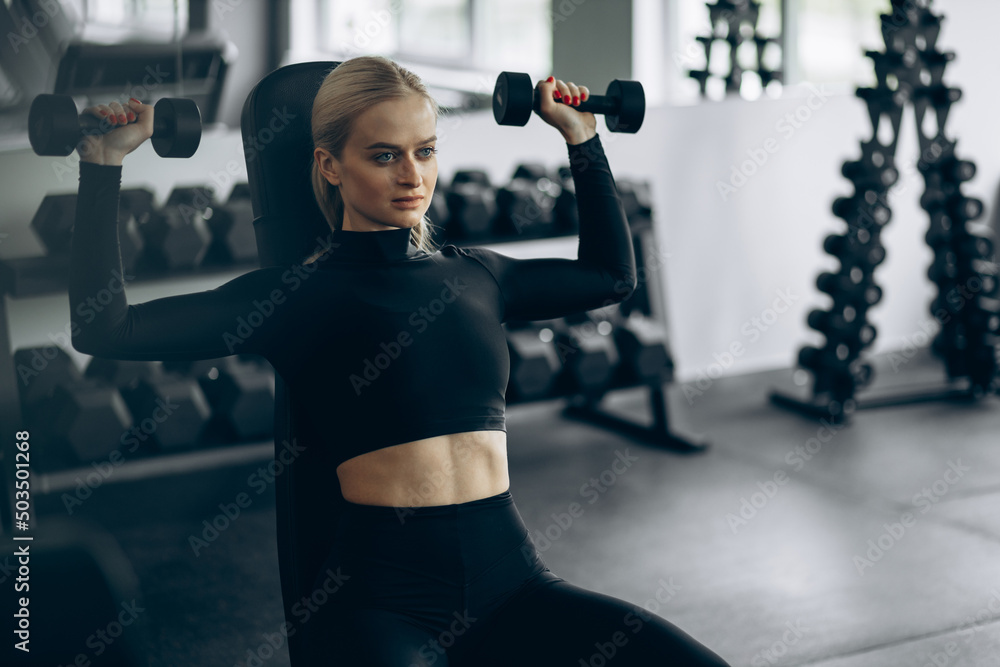 Young woman exercising with dumbbells at the gym Young woman exercising with dumbbells at the gym