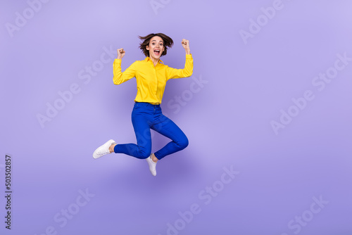 Full length photo of sweet millennial brunette lady jump yell wear shirt pants footwear isolated on purple background