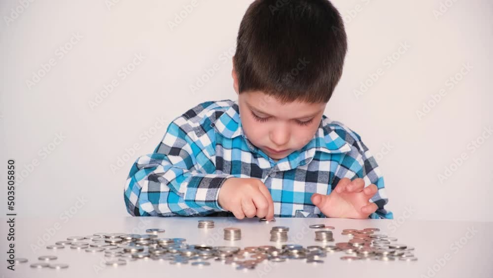 A preschool boy in a plaid shirt counts coins, builds towers. Financial literacy for children. A preschool boy in a plaid shirt counts coins, builds towers. Financial literacy for children.
