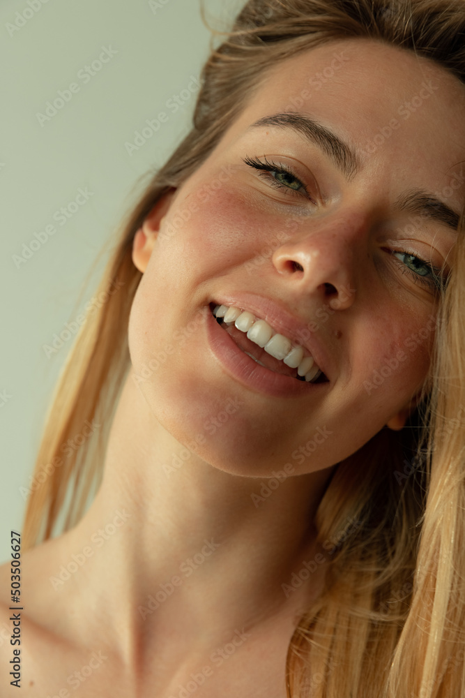 Portrait of young beautiful woman with blush cheeks barely smiling, posing isolated over grey studio background Portrait of young beautiful woman with blush cheeks barely smiling, posing isolated over grey studio background