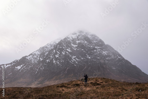 Stunning Winter landscape looking across Rannoch Moor in Scottish Highlands towards Buachaille Etive Mor Stob Dearg with unidentified photogrpher in foreground
