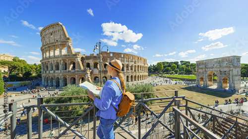  Happy woman tourist looking up from map at Rome Colosseum