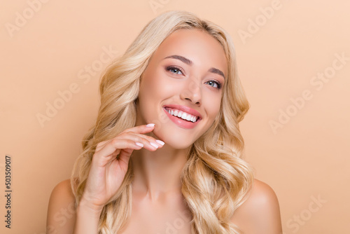 Portrait of attractive cheerful adorable wavy-haired girl touching soft skin cleansing pore isolated over beige pastel color background