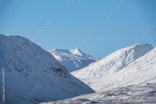 Gorgeous Winter landscape blue sky image of view along Glencoe Rannoch Moor valley with snow covered mountains all around © veneratio