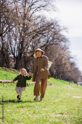 full length view of pleased mother and daughter in stylish clothes walking in green park. © LIGHTFIELD STUDIOS