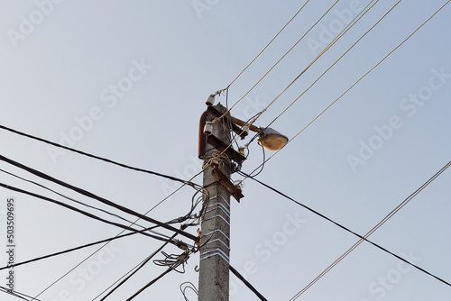 Street cement lamppost with cables on sky background. 