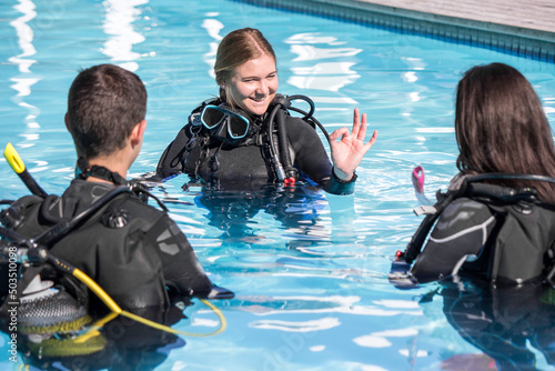 Scuba dive training in the pool with an instructor showing the OK sign to two students