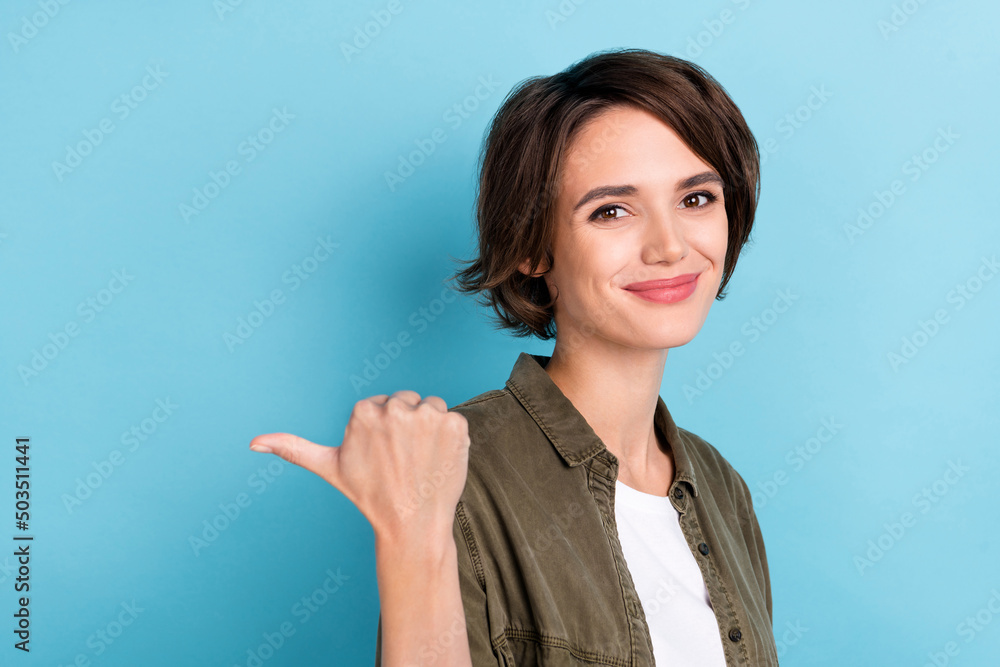 Photo of cute young brunette hairdo lady index empty space wear khaki shirt isolated on blue color background Photo of cute young brunette hairdo lady index empty space wear khaki shirt isolated on blue color background