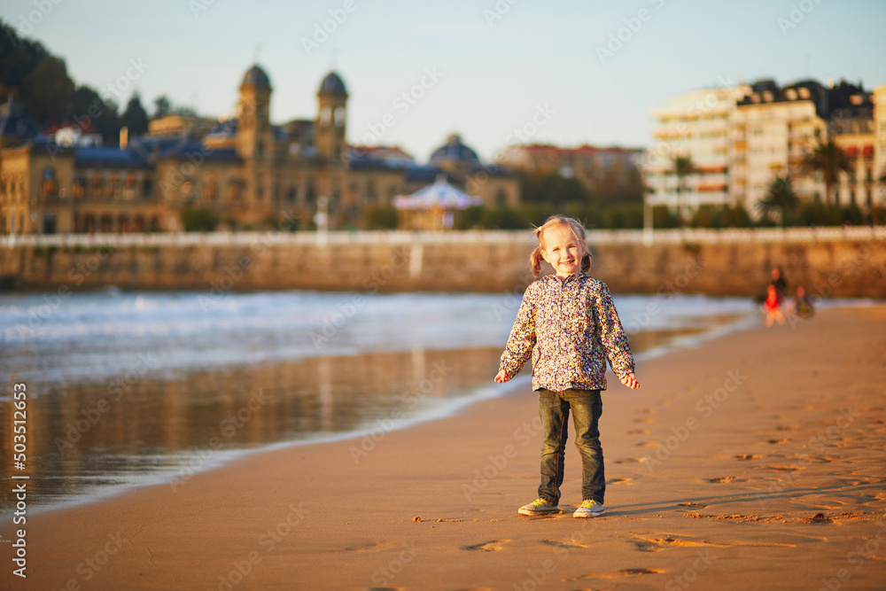 Obraz premium Happy little girl on La Concha beach in San Sebastian, Basque Country, Spain
