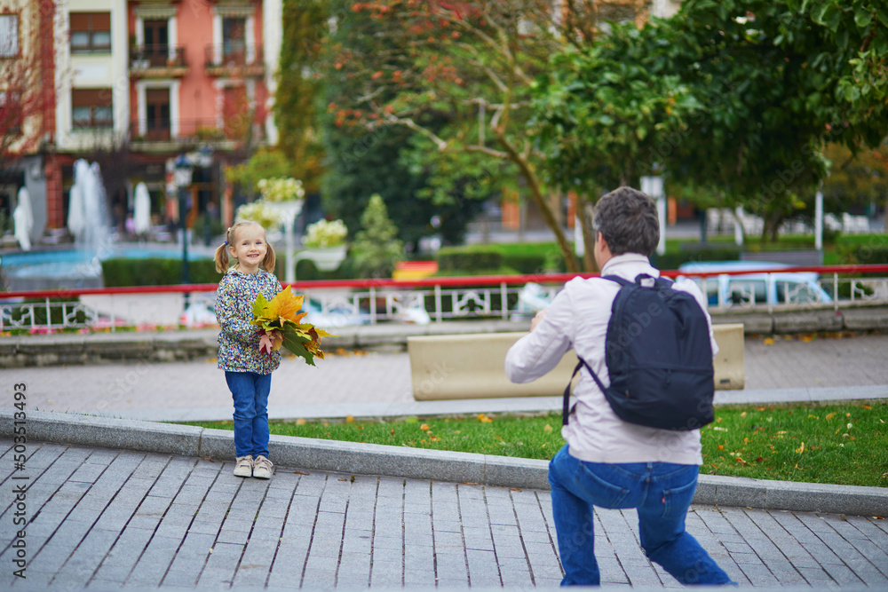 Father taking photo of his daughter on a street of Guernica, Basque Country, Spain Father taking photo of his daughter on a street of Guernica, Basque Country, Spain