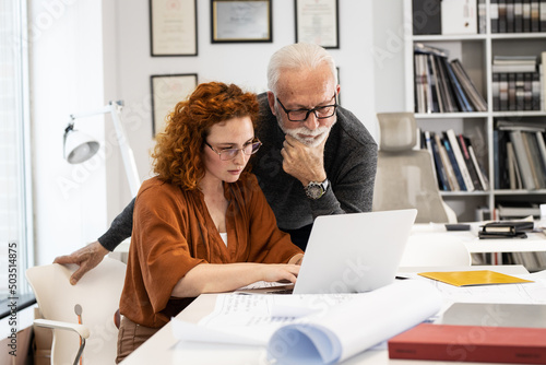 Quadro em tela A senior designer helps his young female coworker to solve a problem