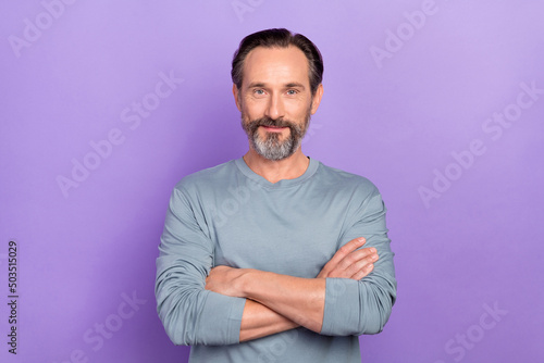 Portrait of handsome clever businessman with folded hands working in modern big company isolated on violet color background