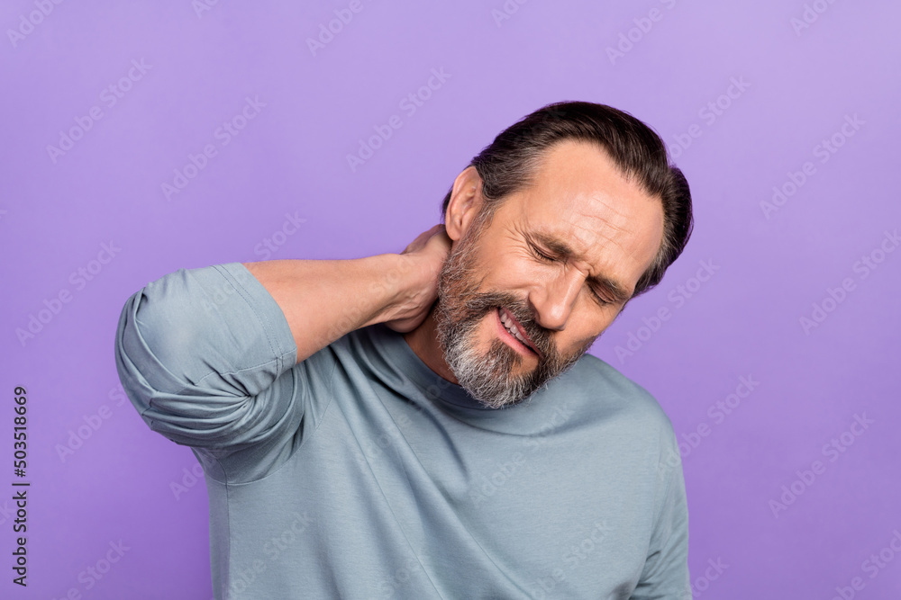 Photo of unsatisfied suffering adult man closed eyes hand touch neck isolated on purple color background Photo of unsatisfied suffering adult man closed eyes hand touch neck isolated on purple color background