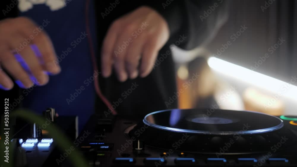 Close up dj hands disc jockey mixing music on his deck with his hands poised over the vinyl record on cd turntable in night club Close up dj hands disc jockey mixing music on his deck with his hands poised over the vinyl record on cd turntable in night club